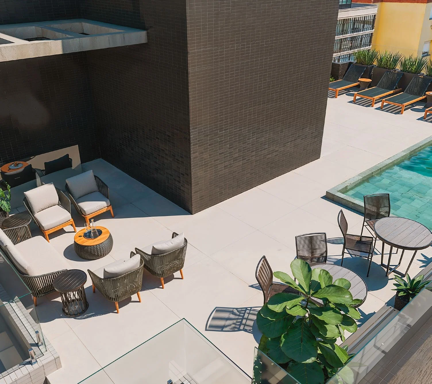 Lounge do rooftop com poltronas, mesas e borda da piscina vistos do alto, Residencial Anita em Capão da Canoa