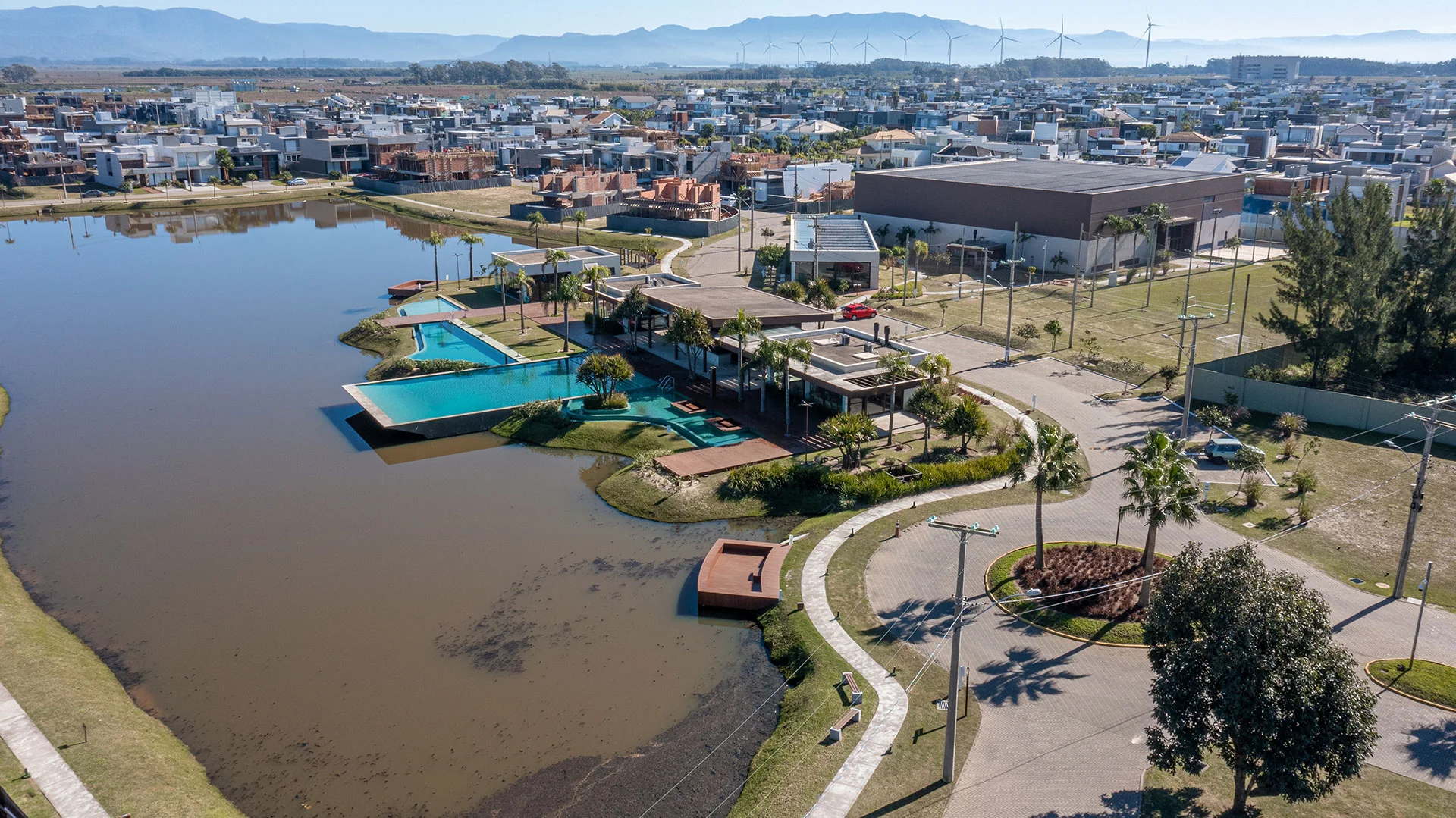 Foto aérea do conjunto do clube do Blue Xangri-lá com piscinas, estacionamento e prédio do ginásio ao fundo