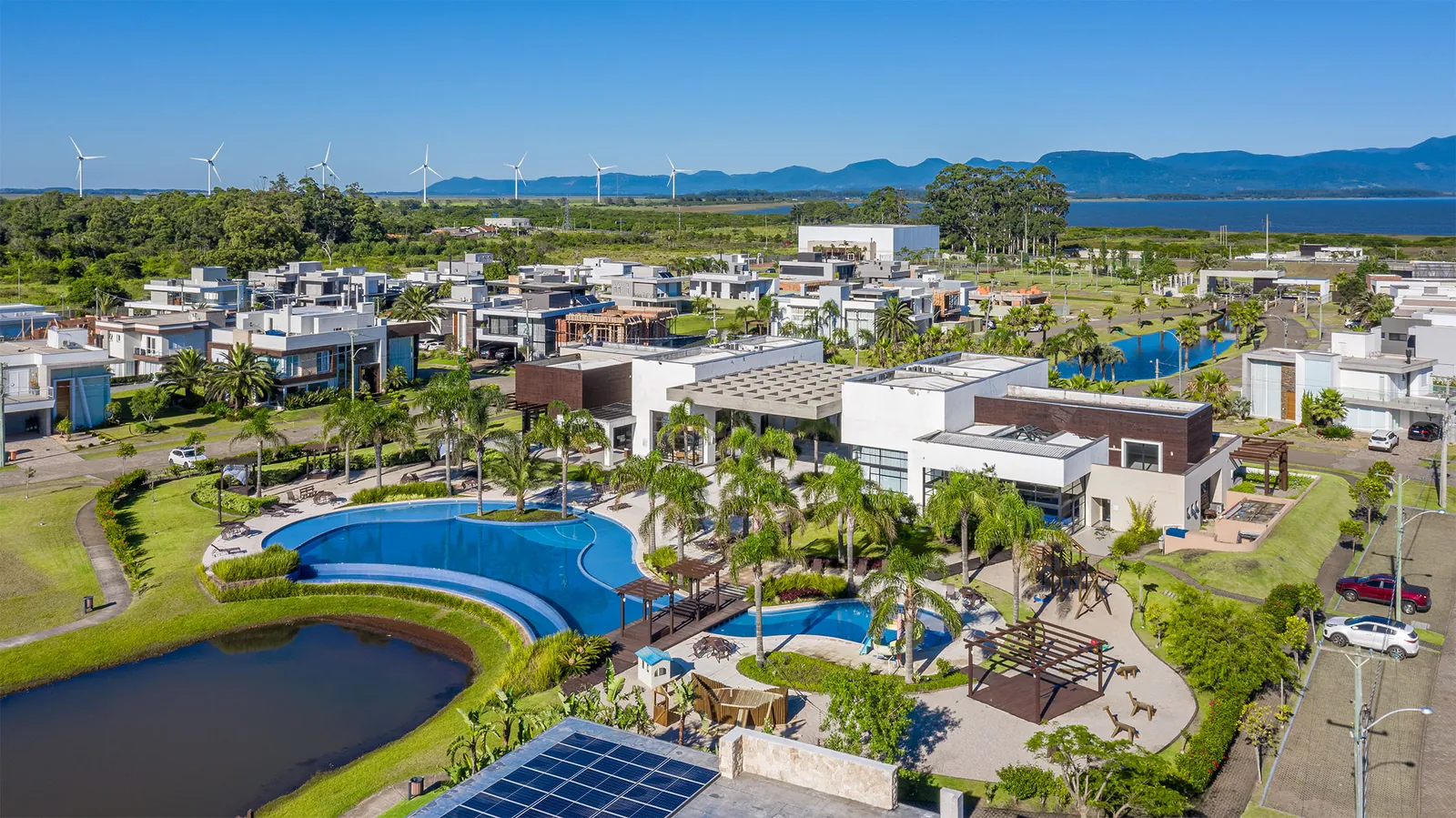 Foto aérea do Clube da Lagoa do Capão Ilhas Resort, piscina em formato de S com deck e jardim