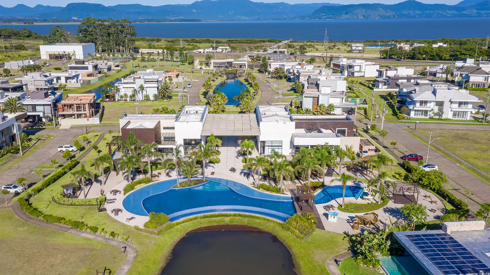 Foto aérea do Capão Ilhas Resort com piscina do clube de lazer e vista para a Lagoa dos Quadros e a Serra do Mar