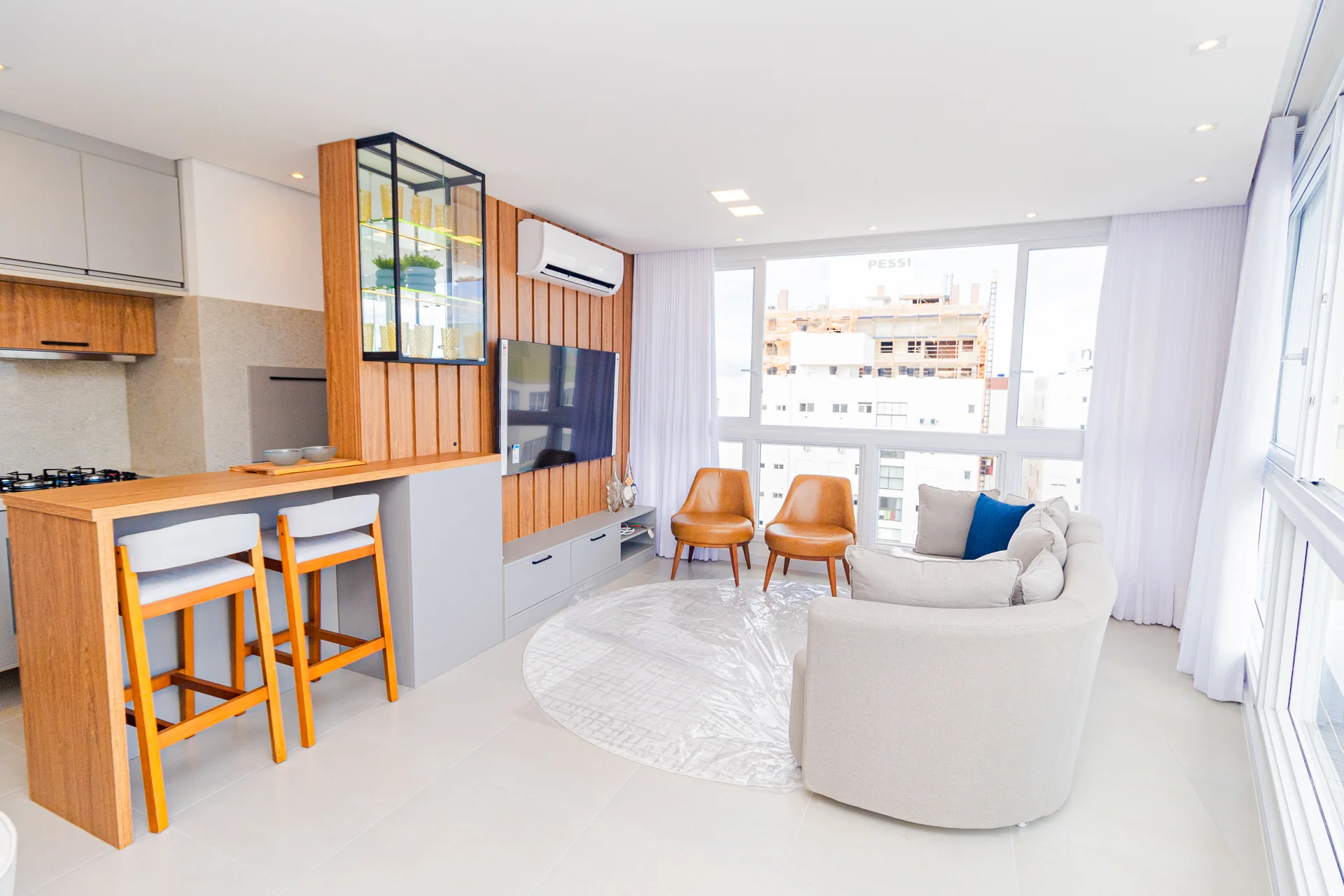 Sala de estar do apartamento decorado do Del Paine, sofá, TV, poltronas e janelão com vista de Capão da Canoa