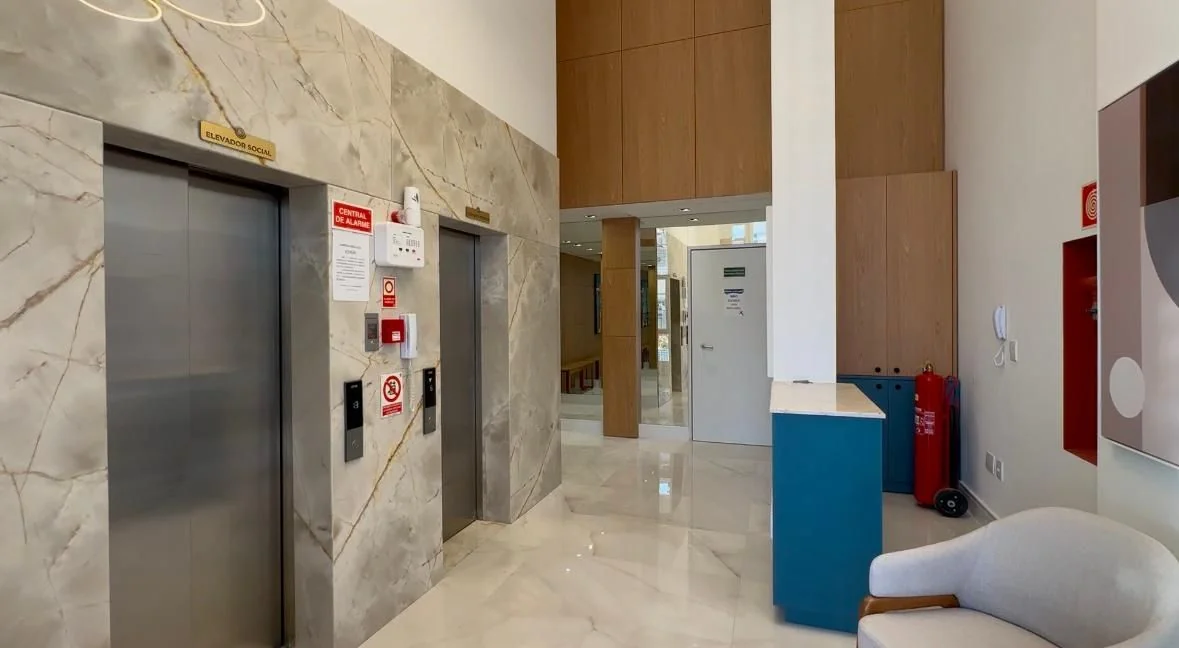 Hall de entrada do Domênico Home & Club com elevadores sociais e acabamento em mármore