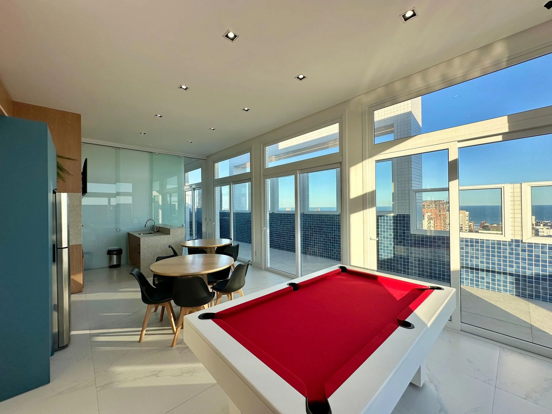 Foto real da sala de jogos no rooftop do Domênico Home & Club, com mesa de sinuca e vista para o mar