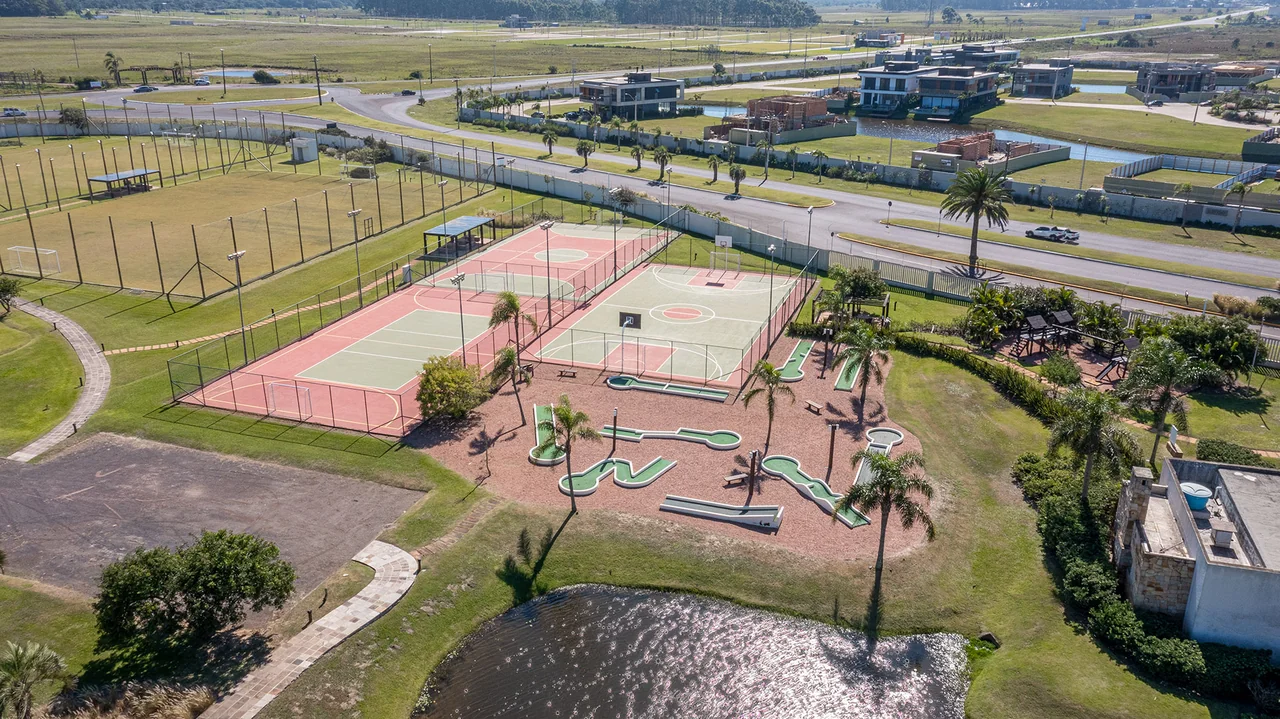 Foto do minigolfe infantil do Enseada Lagos de Xangri-Lá entre palmeiras adultas, junto ao lago do condomínio