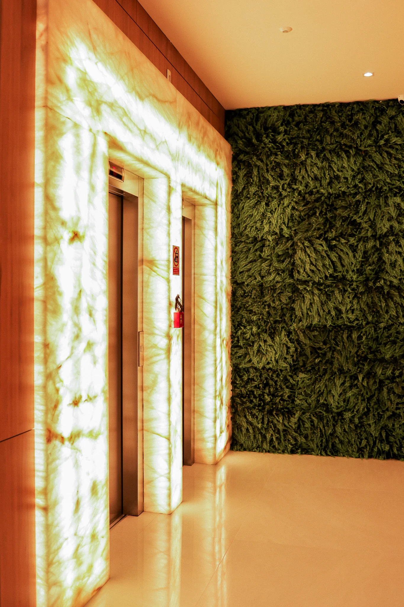 Hall de entrada decorado do Epic Residence, com pé-direito duplo e mármore onyx retroiluminado, em Capão da Canoa