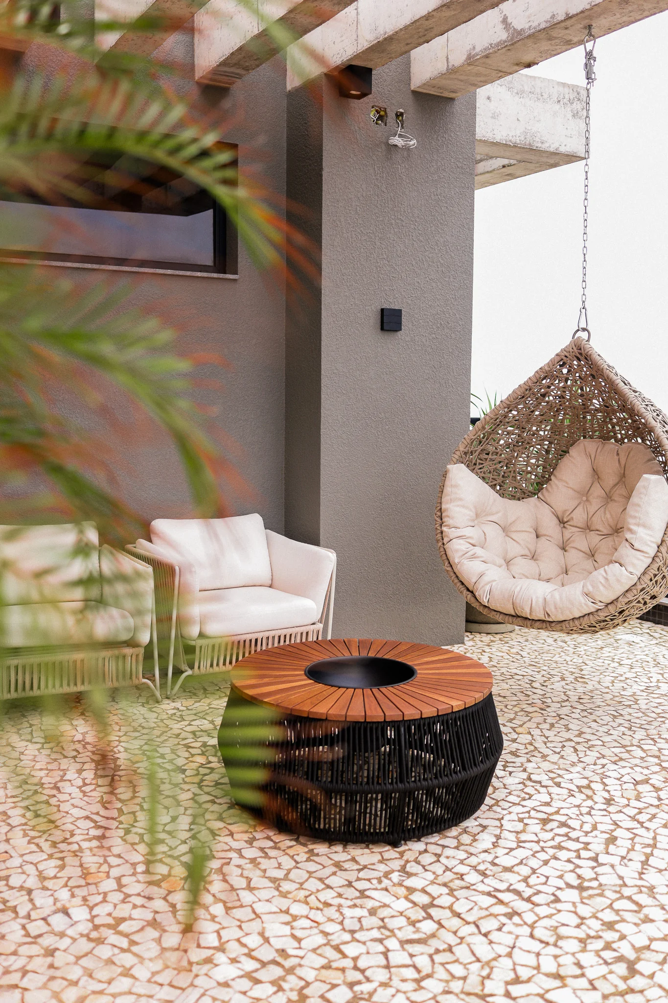 Foto real do espaço zen do rooftop do Epic Residence com poltrona suspensa e lareira