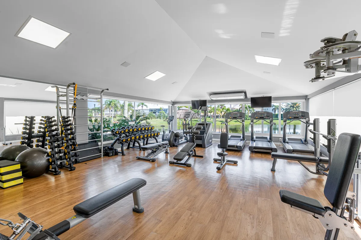 Sala de fitness do clube do Atlântida Ilhas Park, com esteiras, halteres e vista para o canal interno