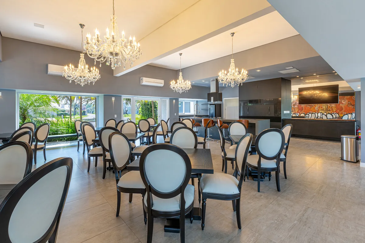 Interior do salão de festas e restaurante do clube do Atlântida Ilhas Park, com lustres e cozinha industrial aberta