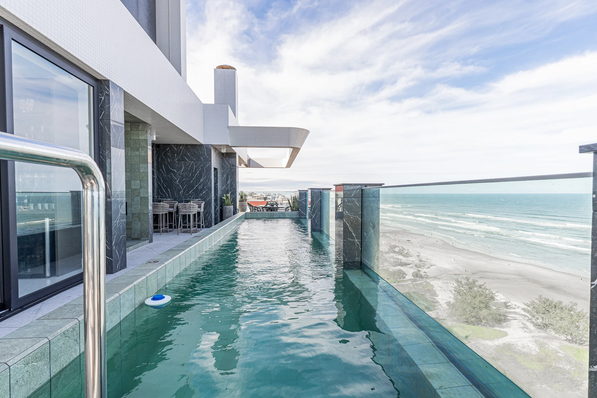Piscina aquecida do rooftop do Edifício Joacir Martinello, com visor de vidro e vista para o mar