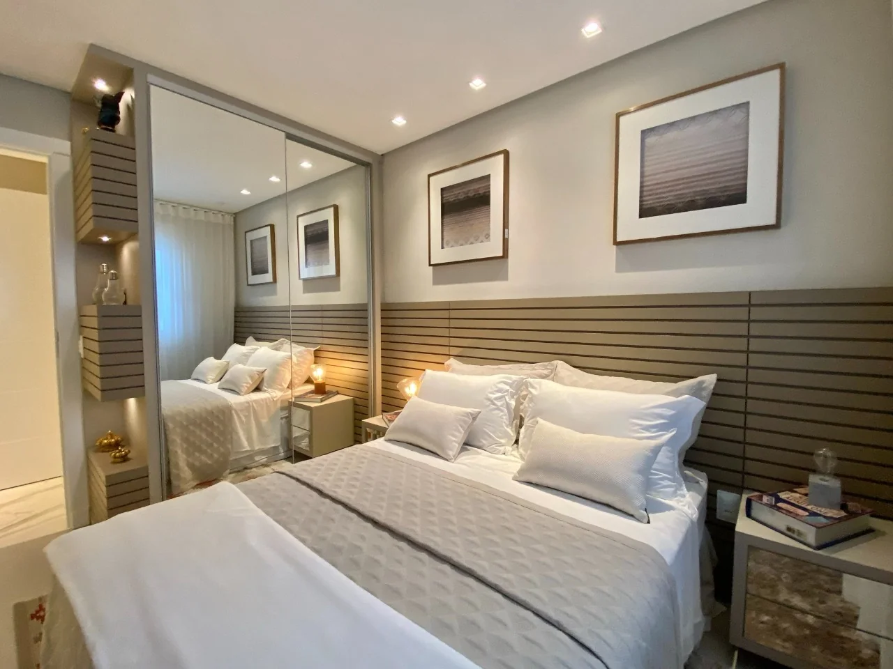 Suíte decorada do apartamento 401 do Edifício João Alves Diniz, com cama de casal, painel ripado de madeira na cabeceira, armário espelhado e criados-mudos