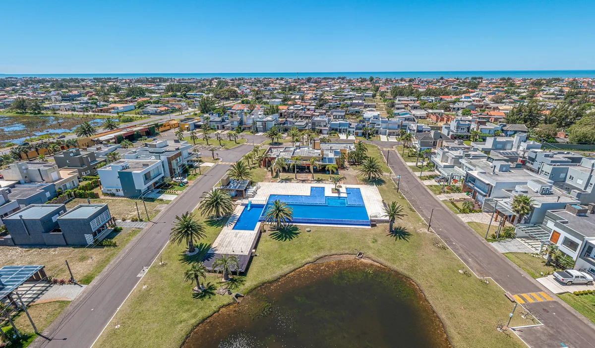 Piscina do clube do Las Palmas em close, com deck de madeira, palmeiras e o clubhouse ao fundo