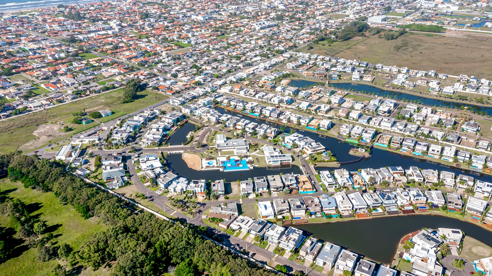 Foto aérea do Malibu Beach Residence com os lagos internos, o clube e as casas junto à água, em Xangri-Lá