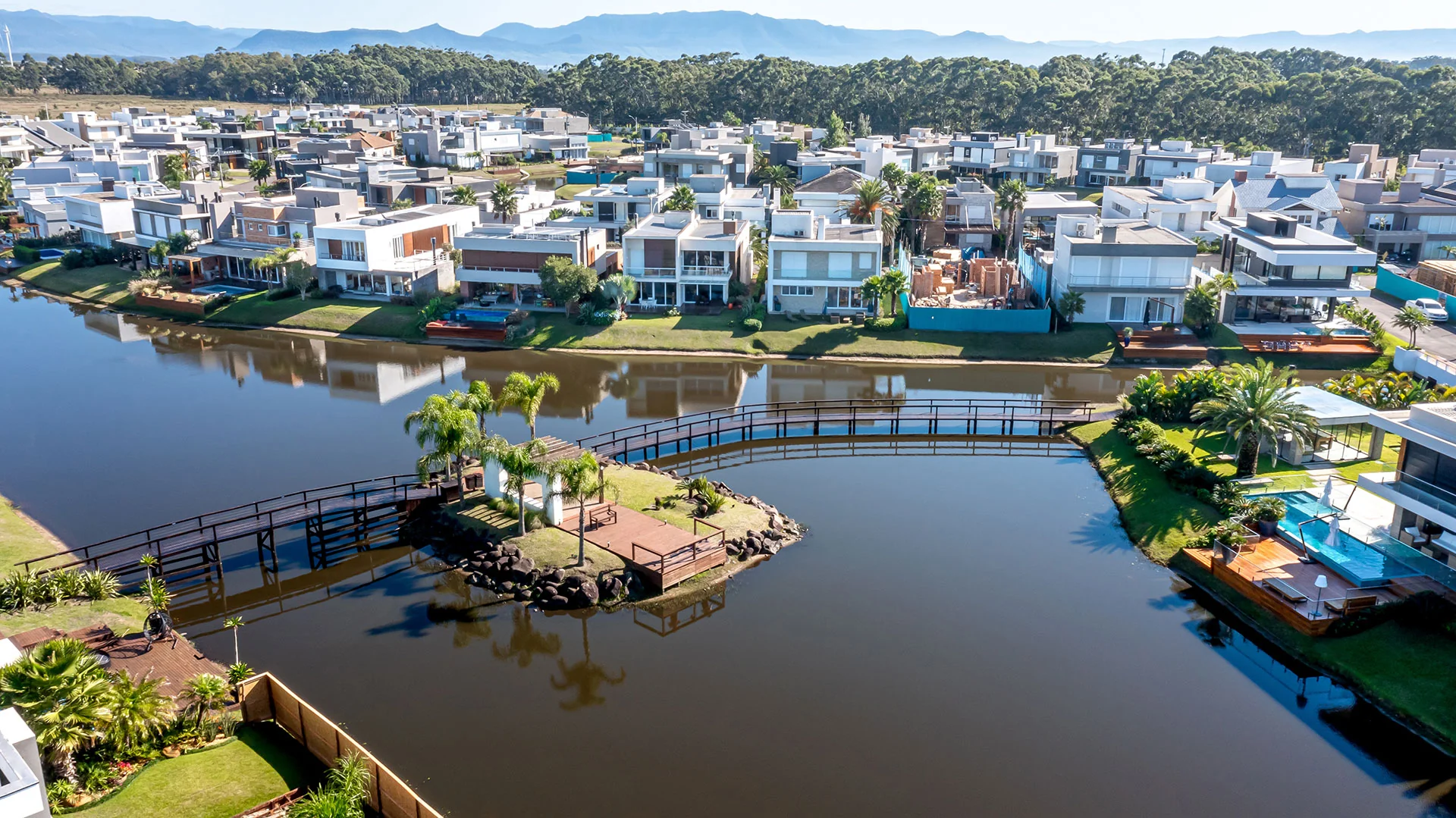 Foto aérea da ilha de bem-estar do Malibu Beach Residence, ligada por ponte sobre o lago