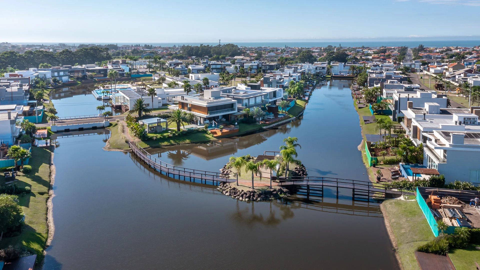 Foto aérea dos lagos internos do Malibu Beach Residence, com ilha, pontes e casas nas margens