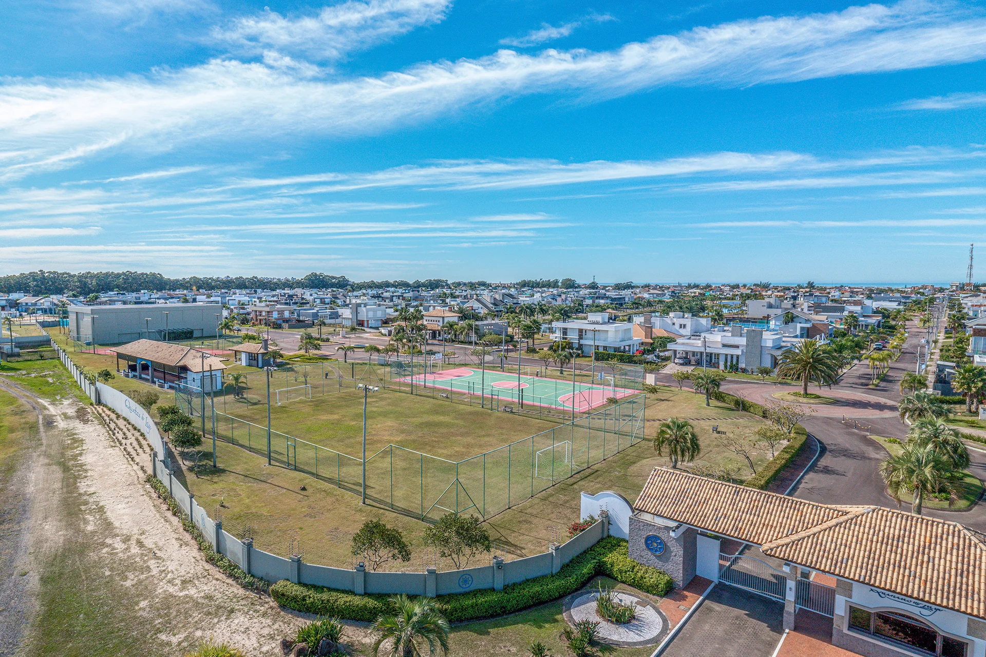 Foto aérea do campo de futebol soçaite e da quadra poliesportiva do Quintas do Lago, junto à portaria