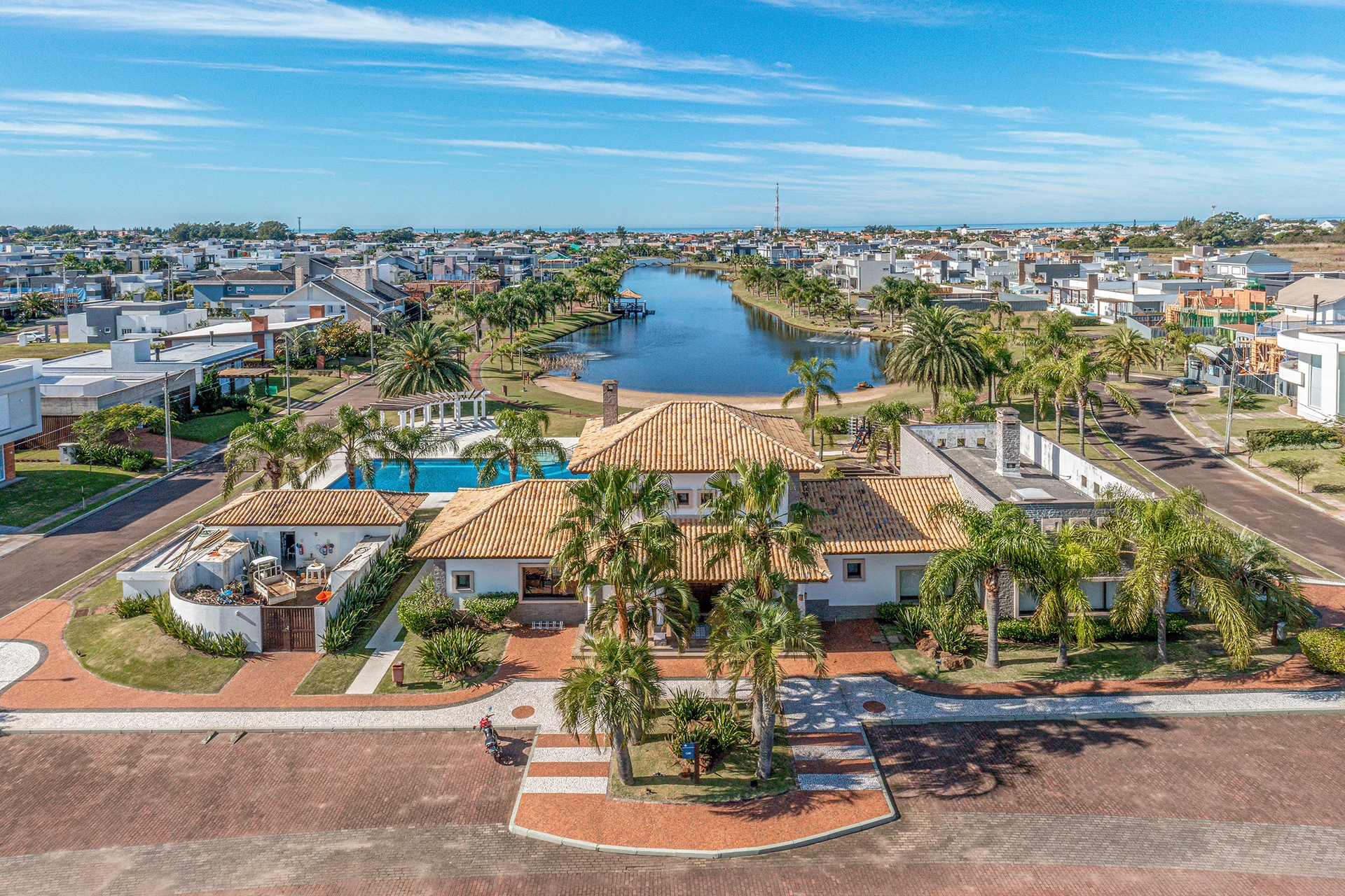 Foto aérea do Quintas do Lago com o lago central, ponte em arco, clube e casas ao redor, em Xangri-Lá