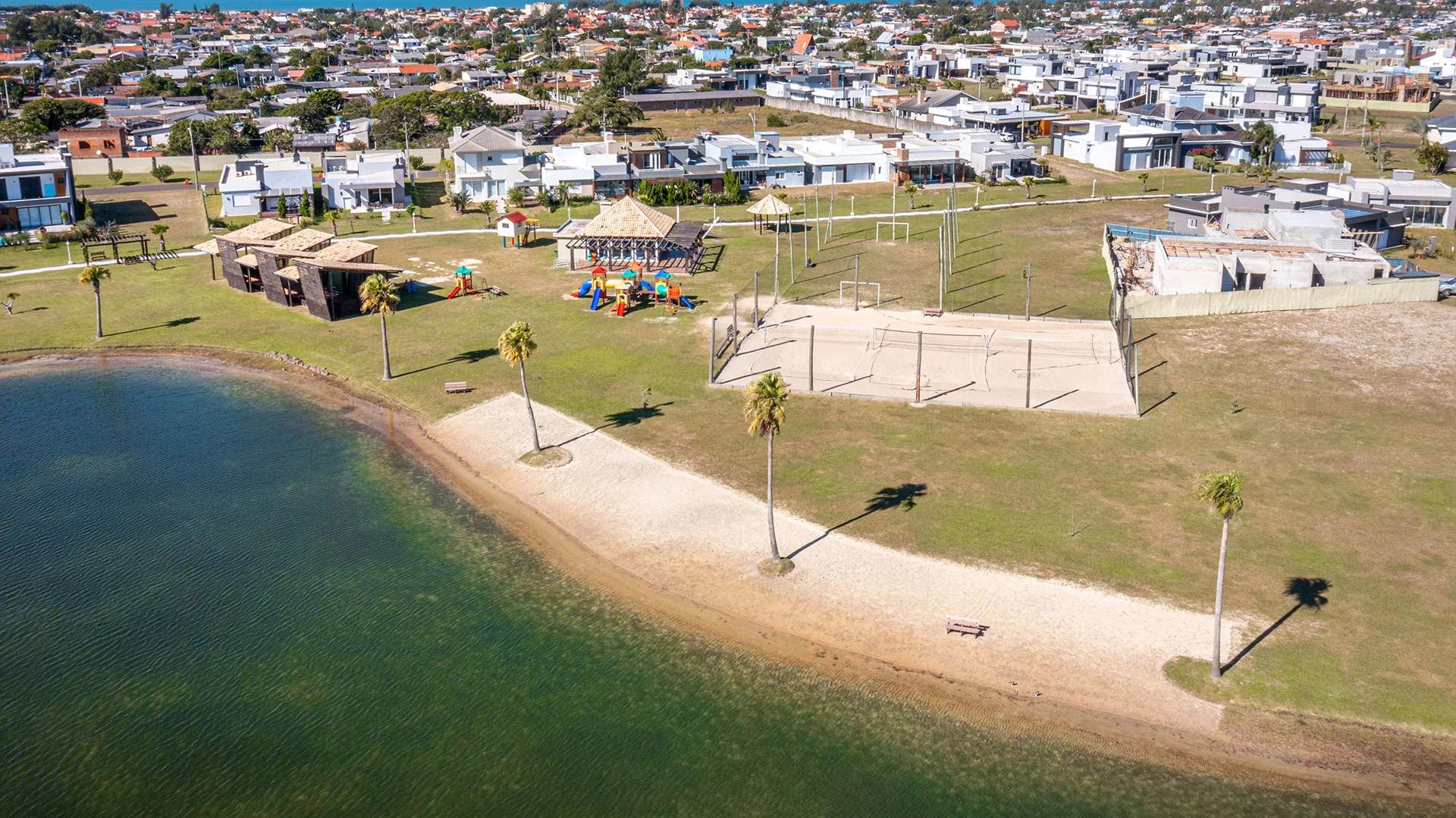 Foto aérea de um lago interno do Riviera com margem de areia e quadra esportiva de areia