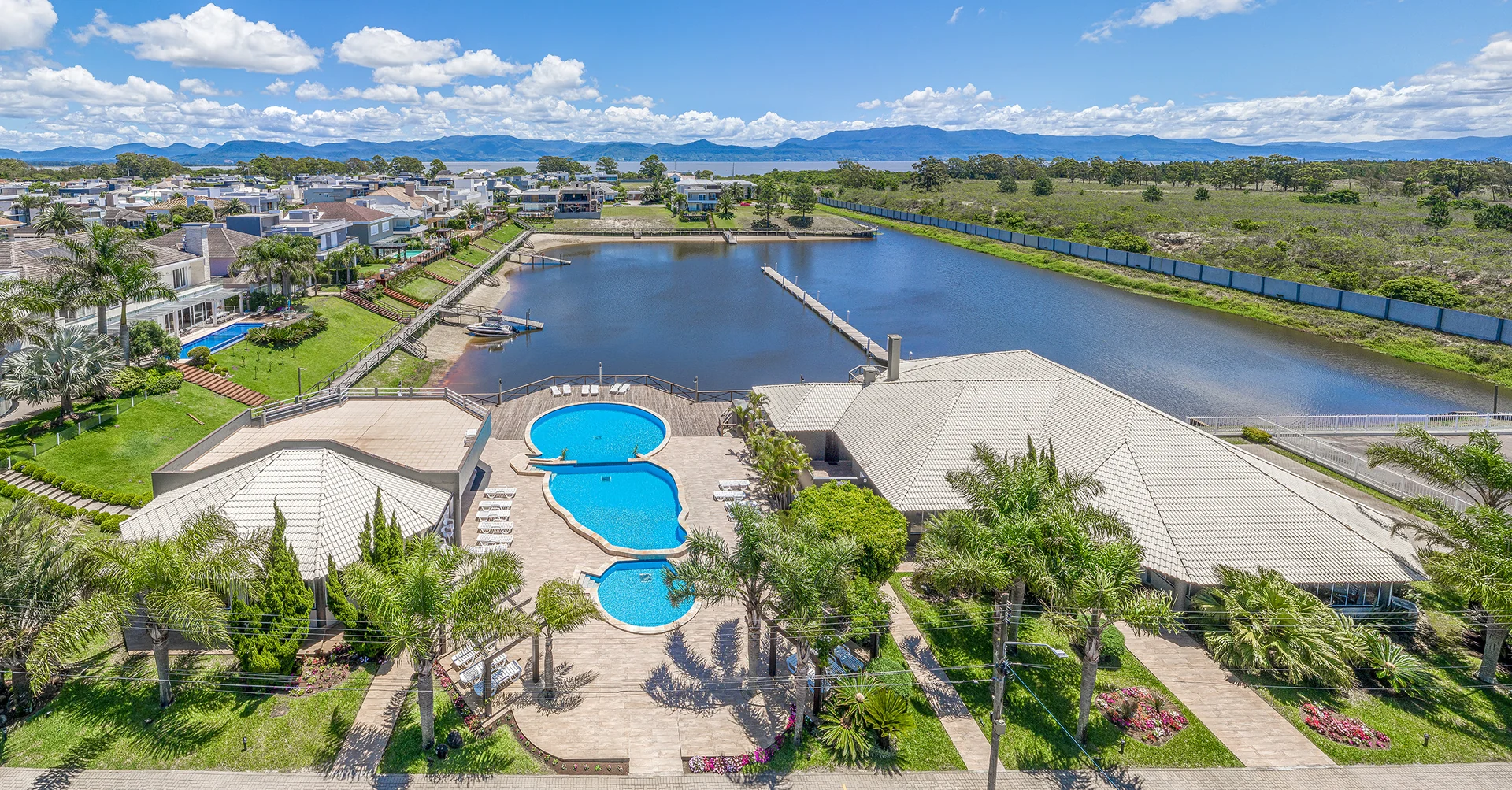 Foto aérea do Velas da Marina com o clube, as piscinas, o canal e as marinas junto à Lagoa dos Quadros, em Capão da Canoa