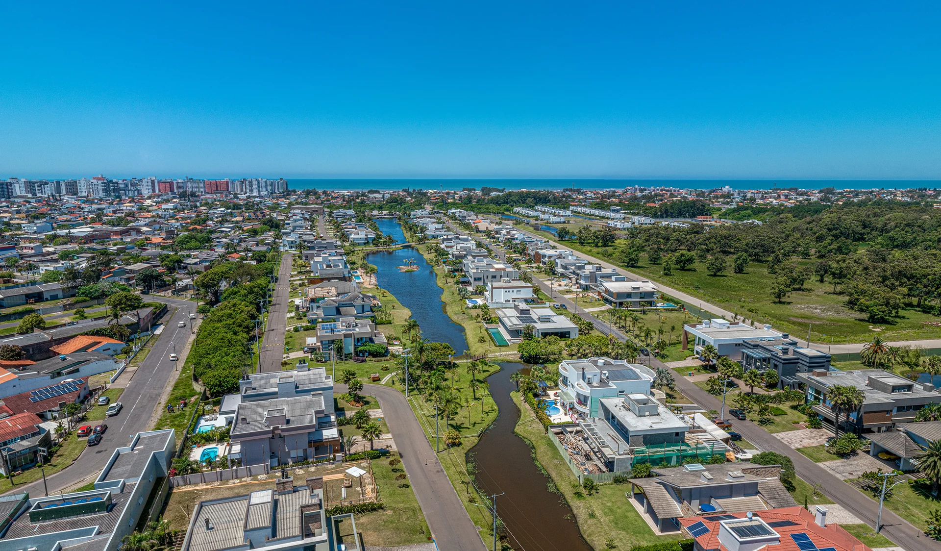 Vista aérea completa do Villaggio Atlântida com o skyline de prédios de Xangri-Lá e o mar ao fundo