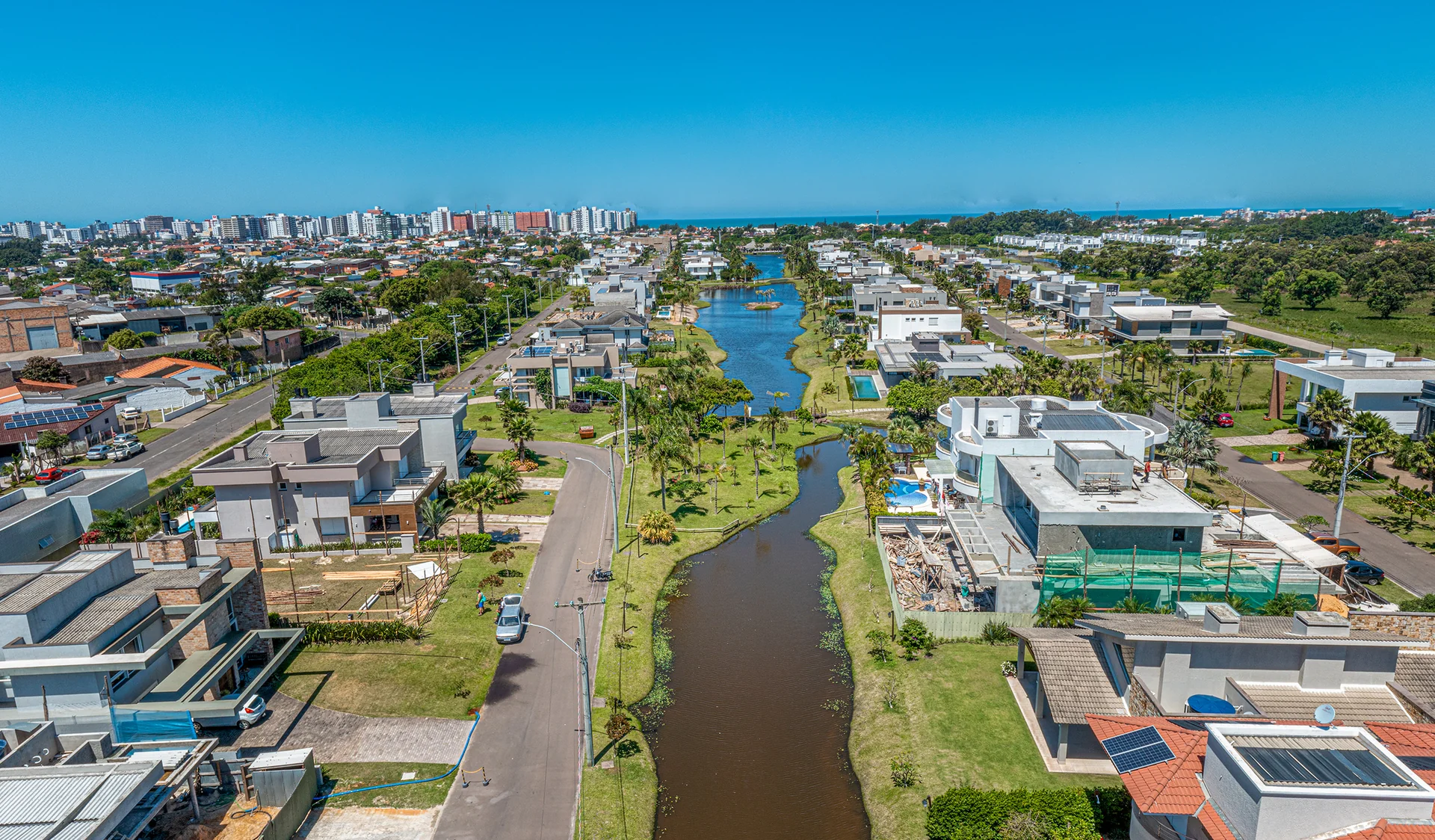 Foto aérea do Villaggio Atlântida com o canal central, casas com piscina nas margens e a ilha do clube, no bairro Atlântida de Xangri-Lá